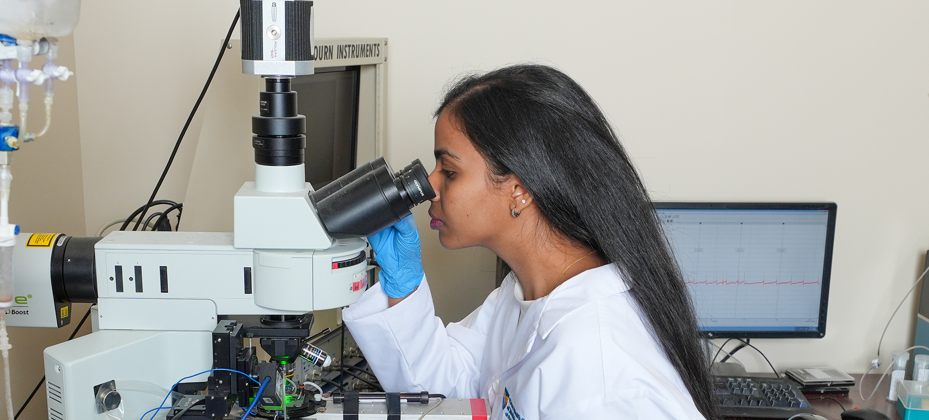 a research student looks at a specimen in the microscope
