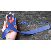 a blue ribbon lays across a hand on a table and Colorectal Cancer Awareness is written on top